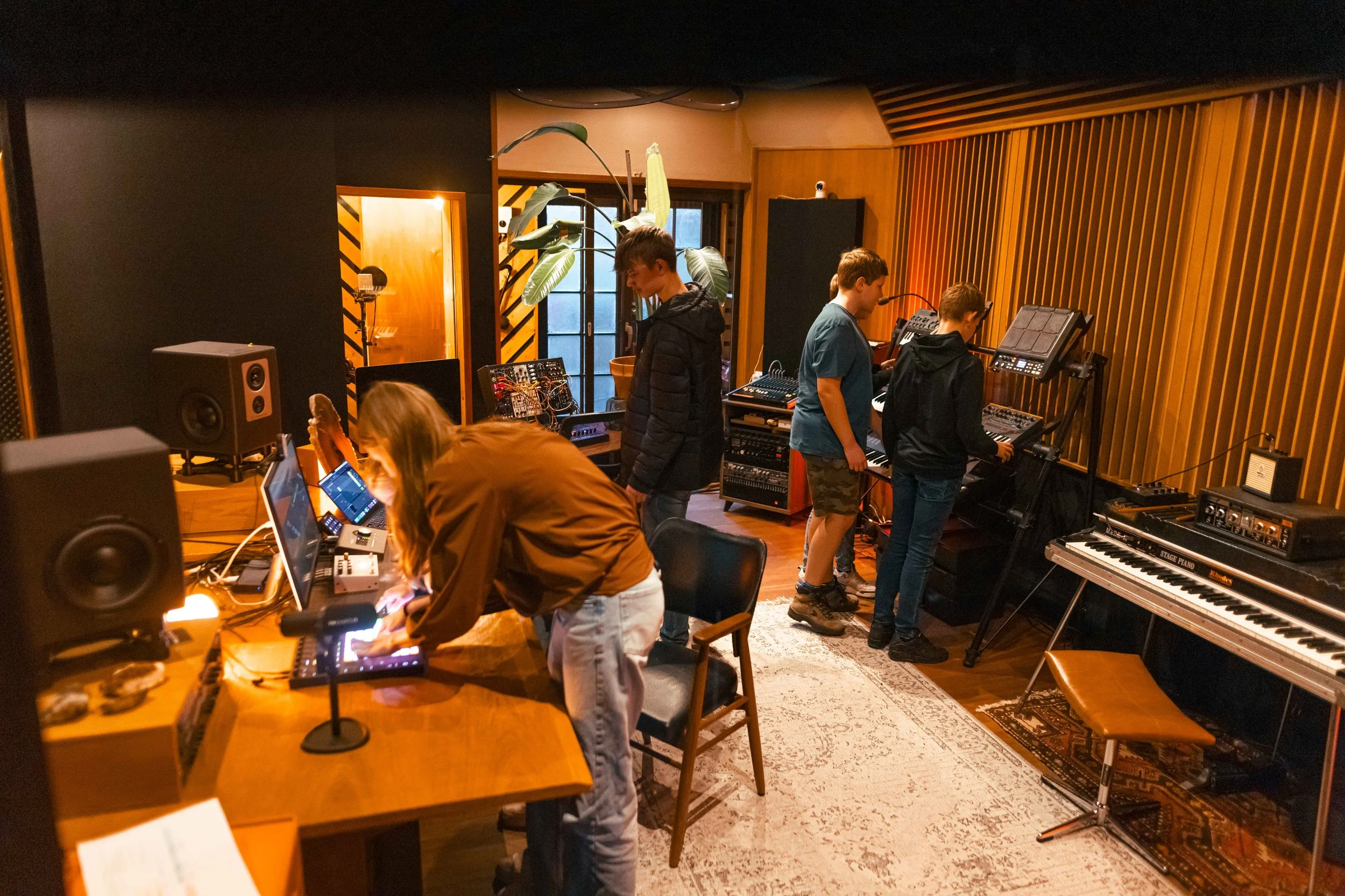 A music studio with four people working on electronic equipment and synthesizers.